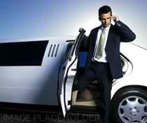 A man in suit and tie standing next to a white limo.