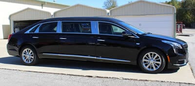 A black limo is parked on the side of the street.